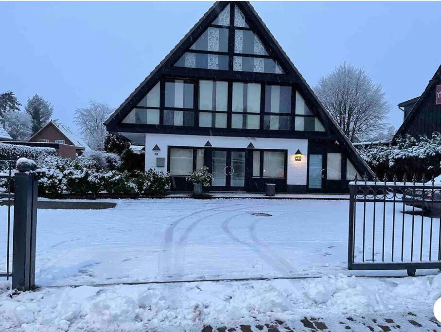 une maison avec un toit en gambrel dans la neige dans l'établissement Neu Guest Place, à Quickborn
