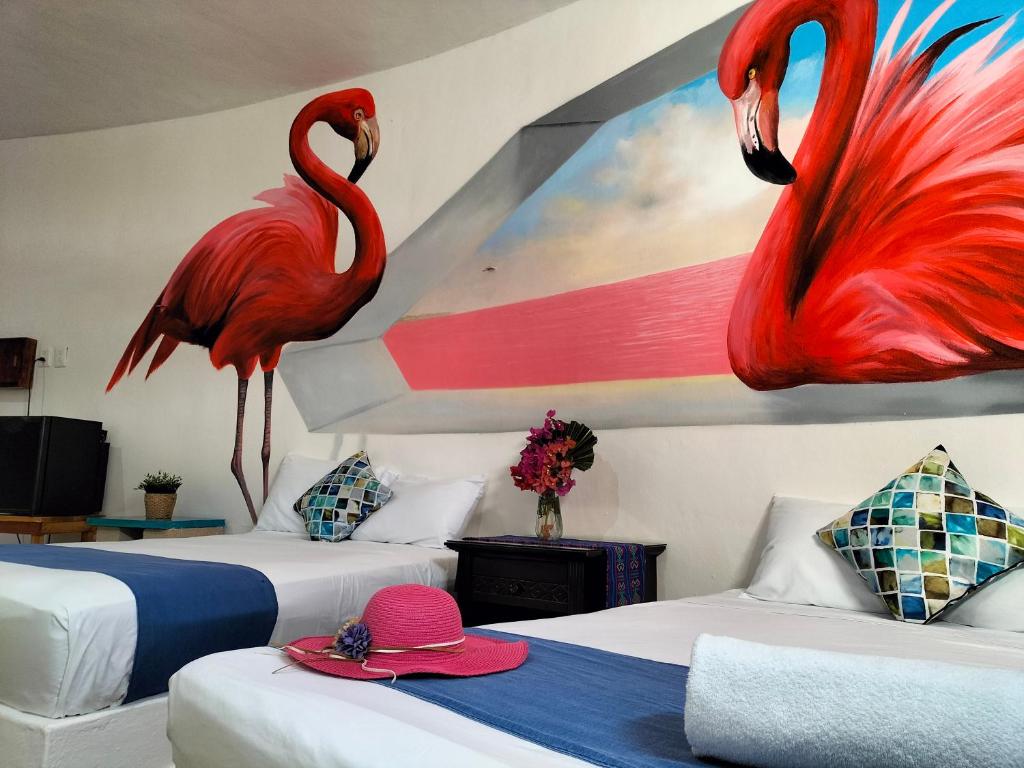 two flamingos on the wall of a room with two beds at HOTEL LAS COLORADAS in Yuluc