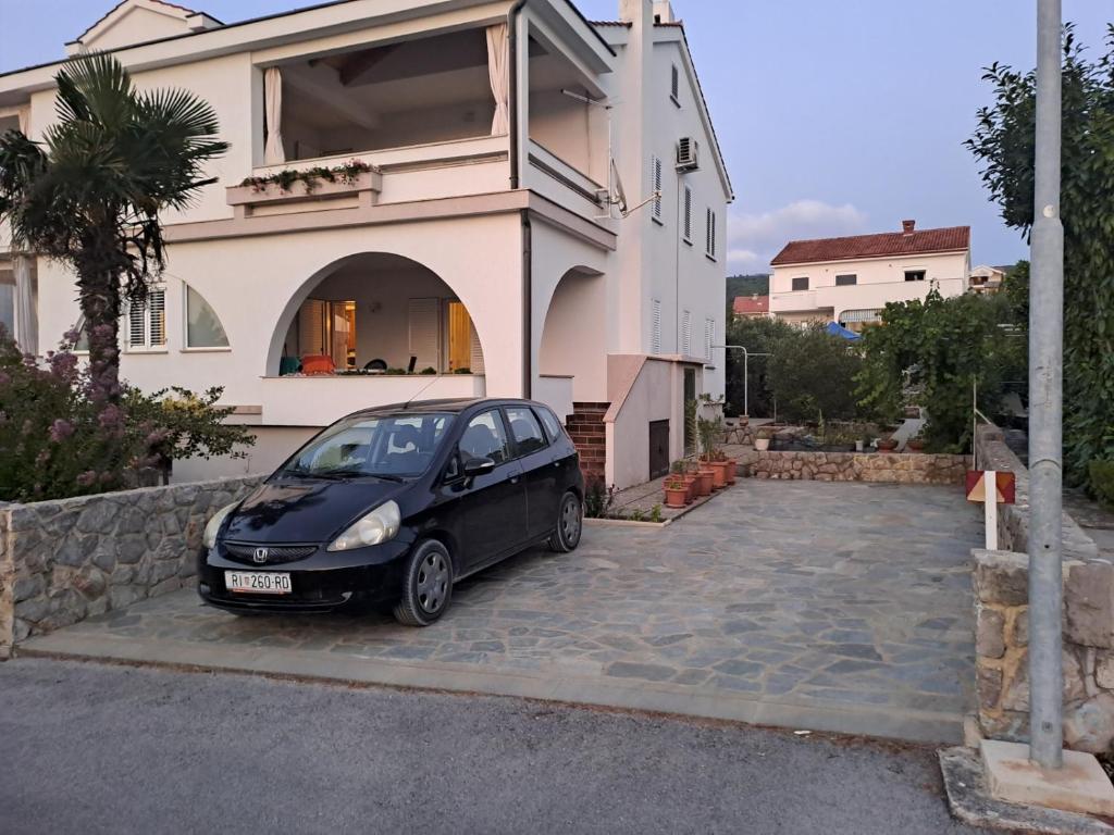 een zwarte auto geparkeerd voor een huis bij Apartment in Punat with Terrace, Air conditioning, Wifi, Washing machine (3829-3) in Punat