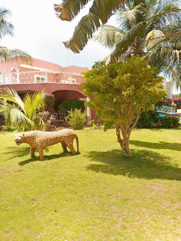 Una statua di un ghepardo nell'erba vicino a un albero di Villa Savana a Somone