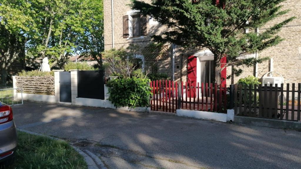 einen Zaun mit einer roten Tür vor einem Haus in der Unterkunft Studio pour 2 personnes in Arles