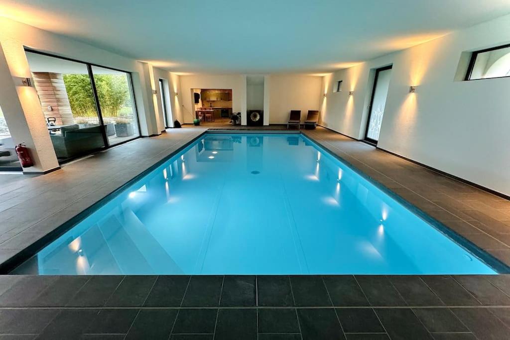 a large swimming pool with blue lighting in a house at Aqua Aura - Deluxe Spa Getaway with Sauna & Pool in Stegen