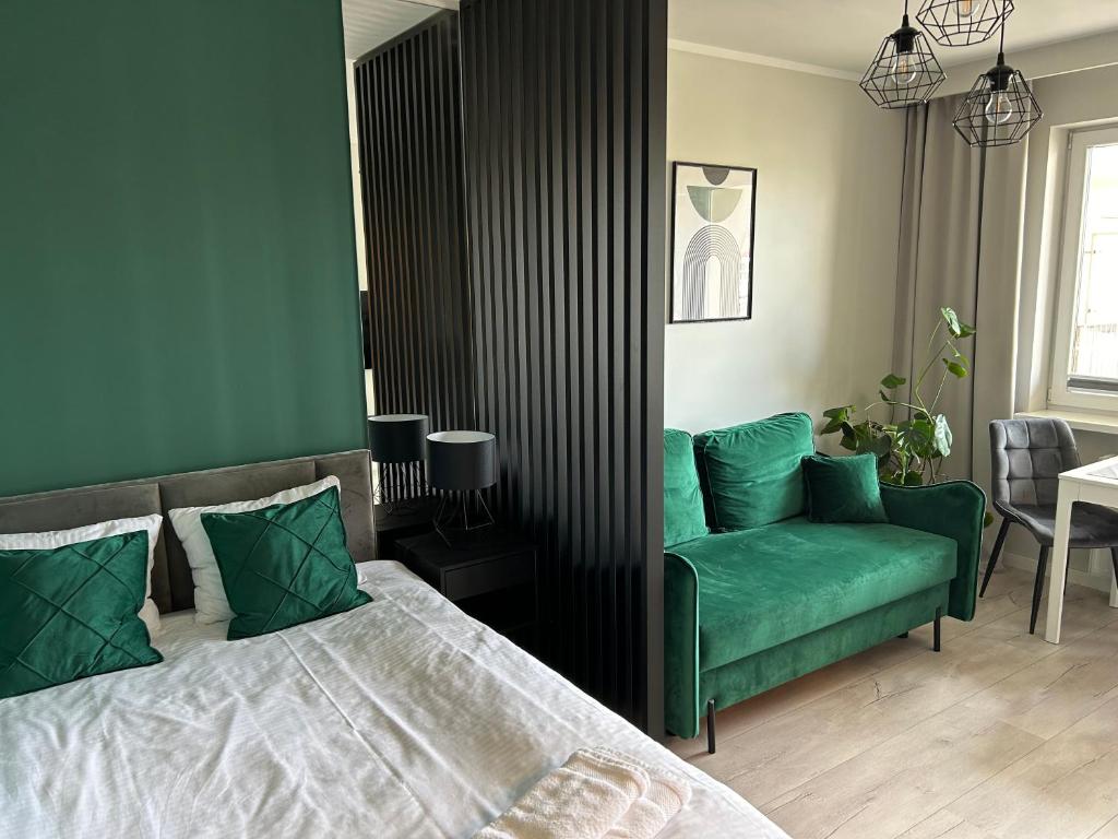 1 dormitorio con 1 cama y 1 sofá verde en Apartament Rataje Park Poznań II - Parking - 24h check in en Poznan