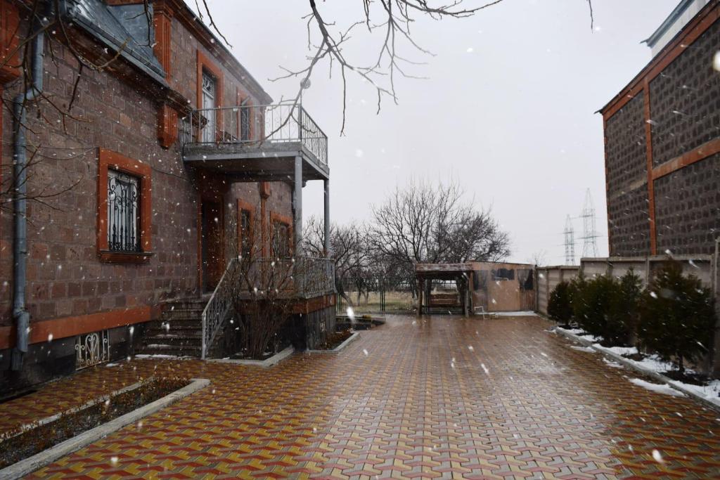 una calle de ladrillo vacía con un balcón en el lateral de un edificio en Вила Eco Garden, en Gyumri