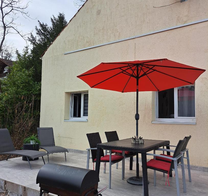 un parapluie rouge assis sur une table avec des chaises dans l'établissement Maison de 2 chambres avec jardin clos et wifi a Saint Cyr la Riviere, 