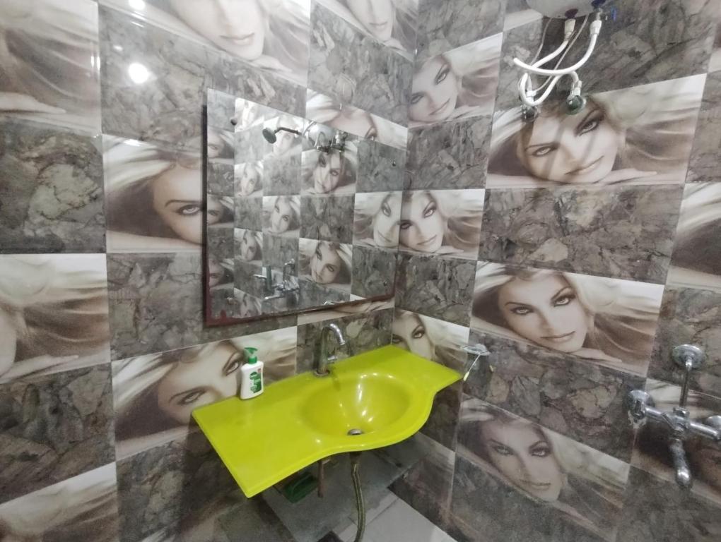 uma casa de banho com um lavatório verde e uma parede de faces em ARVINDAM VILLA HOMESTAY-THE ESSENCE OF RAMA em Ayodhya