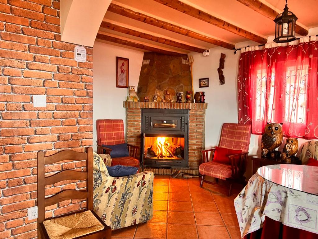 a living room with a fireplace and a brick wall at Cortijo La Solana Montefrío in Montefrío