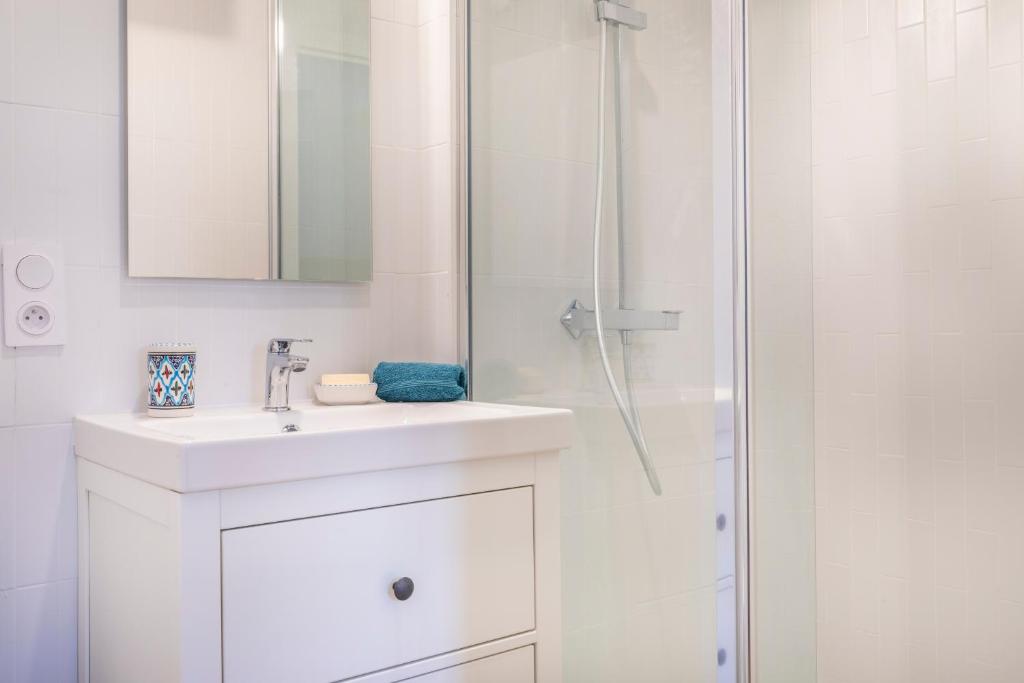 a white bathroom with a sink and a shower at Le Petit Jaune : Centre ville T2 avec balcon in Marseille