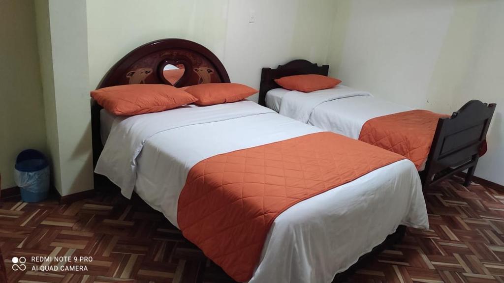 Duas camas com almofadas laranja num quarto em Gran Hostal Casa Luz em Quito