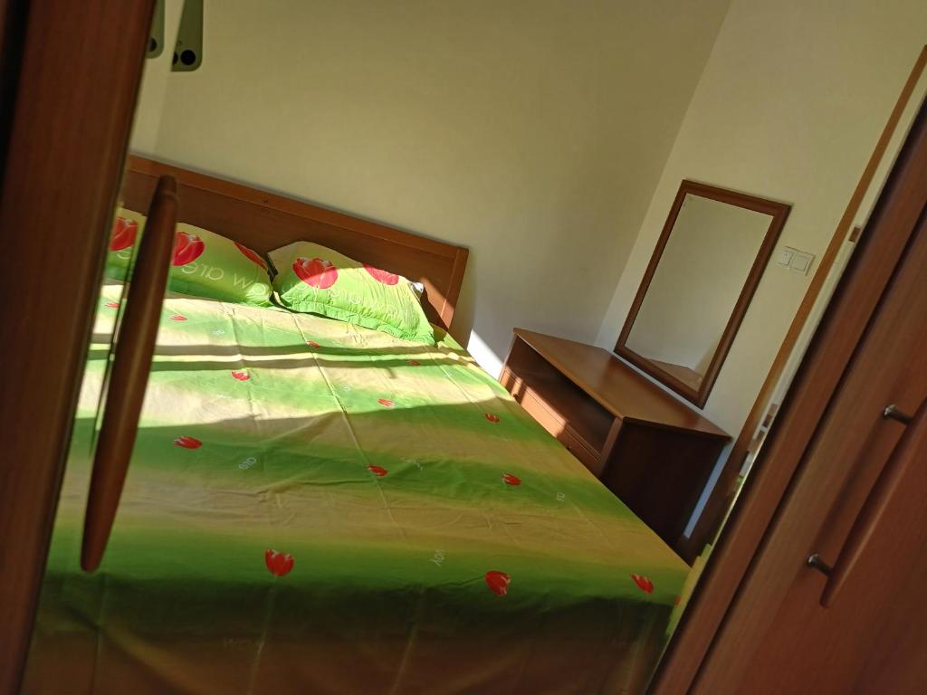 a bed with a green comforter with red flowers on it at Apartman Olja in Radovići
