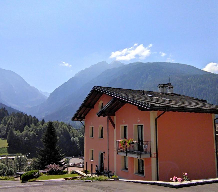 un bâtiment avec un balcon et des montagnes en arrière-plan dans l'établissement Appartamenti Flora Alpina, à Temù