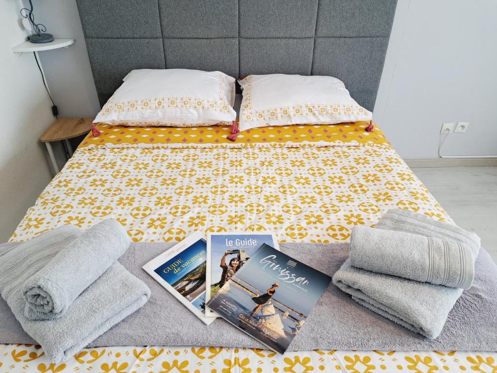 a bedroom with a bed with a book and towels at Studio Moderne - Plage du Grazel in Gruissan