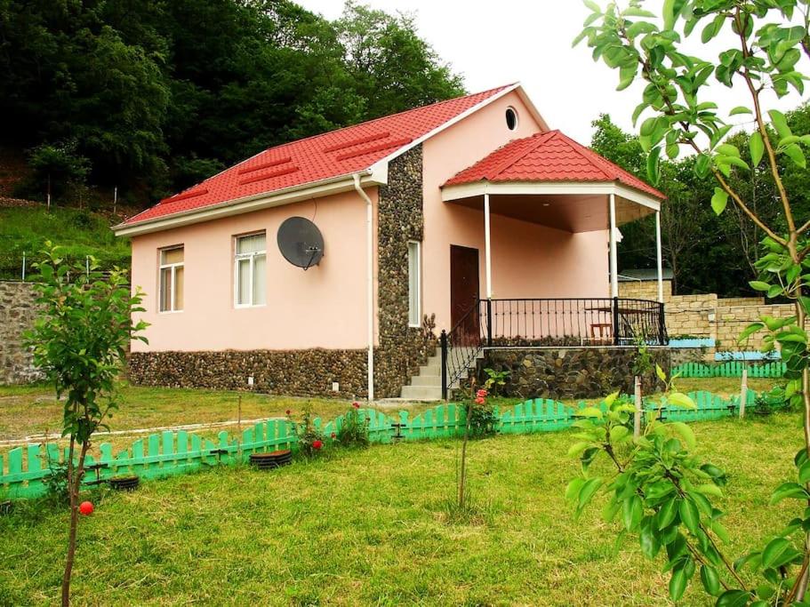 a small house with a red roof in a yard at Guliyev Home in Qax