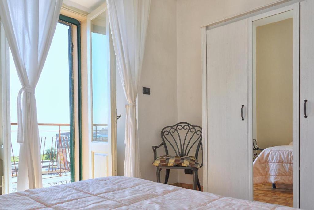 a bedroom with a bed and a chair and a balcony at CASA CHITI TAORMINA in Taormina