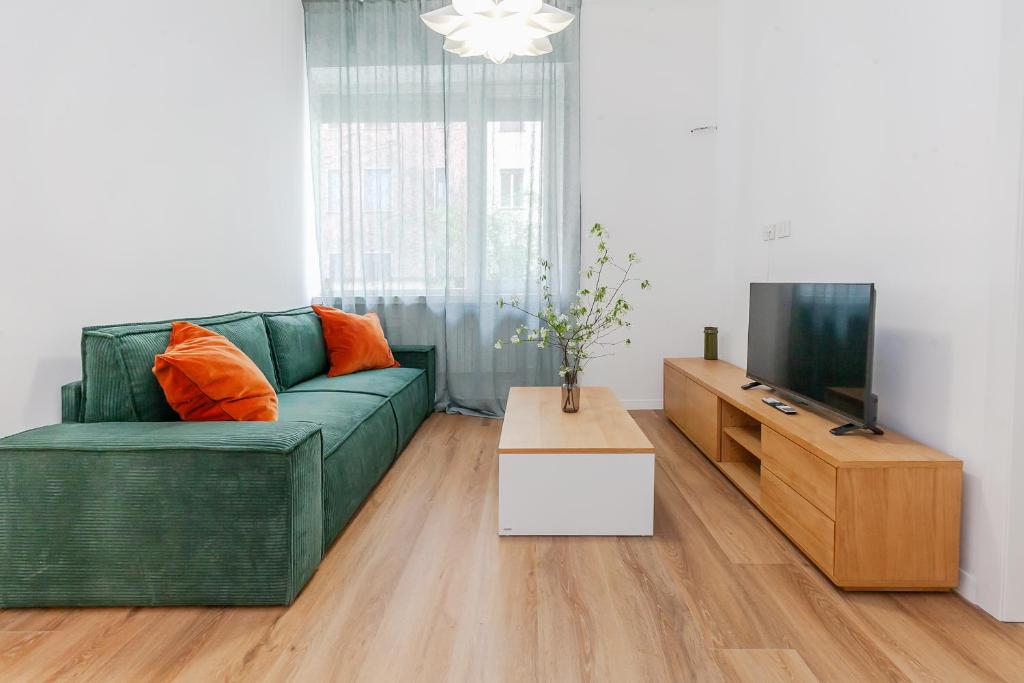 un soggiorno con un divano verde e una TV di Milano Twin Suites - Cozy Chic in Santa Sofia MM4 a Milano