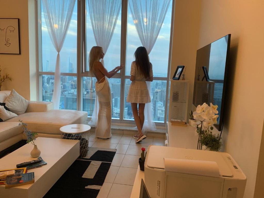 two women standing in a living room looking out of a window at Torch 77 in Dubai