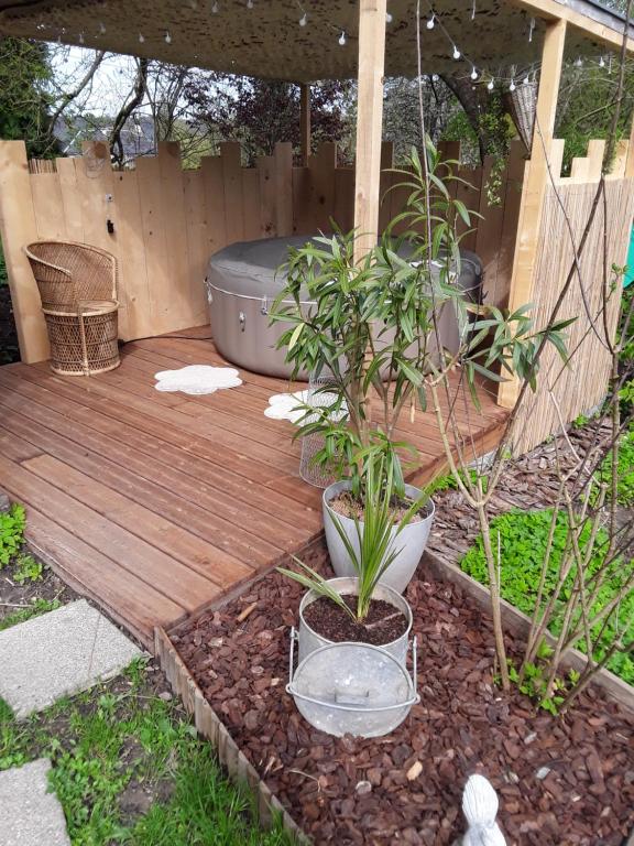 una terraza de madera con 2 plantas en un patio trasero en Un week-end à la campagne, en Pont-Audemer