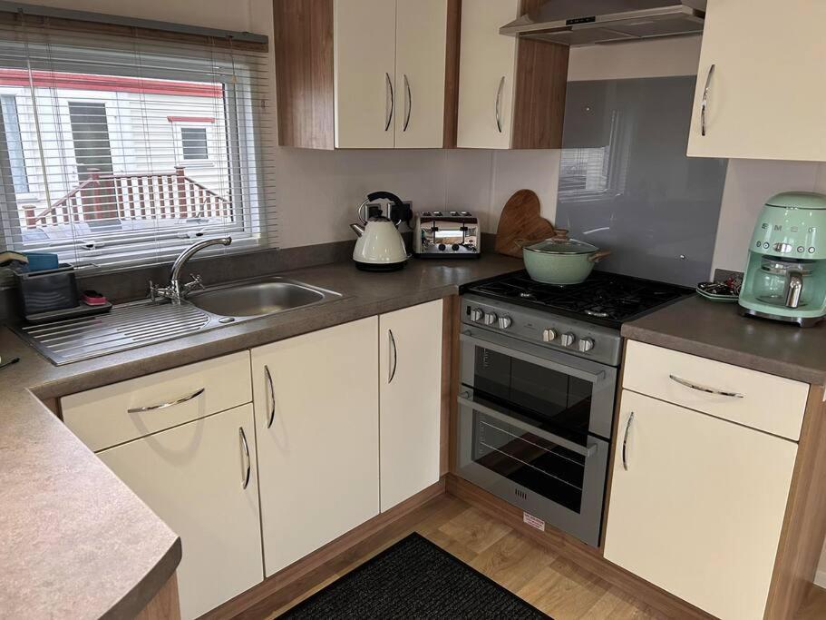 a kitchen with white cabinets and a stove top oven at Red Lion Caravan Park, Arbroath in Arbroath