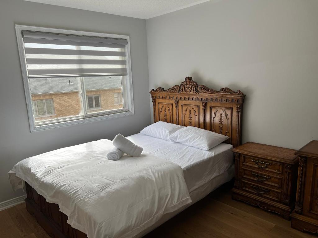 a bedroom with a bed with a wooden headboard and a window at House In Scarborough 20 Minutes to Downtown in Toronto