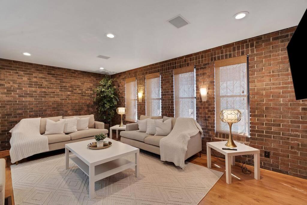 a living room with two couches and a brick wall at Beltline Beauty*Mins to Benz Stadium, Game Room* in Atlanta