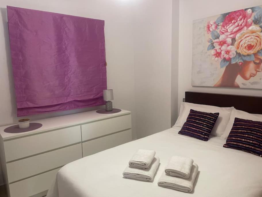 a bedroom with a white bed with towels on it at Disfrutar de la playa in Playa de Gandia