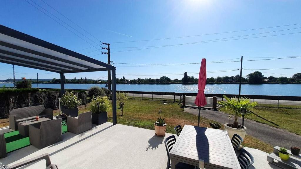 eine Terrasse mit einem Tisch und Stühlen sowie Seeblick in der Unterkunft Val'lo'Seine in Duclair