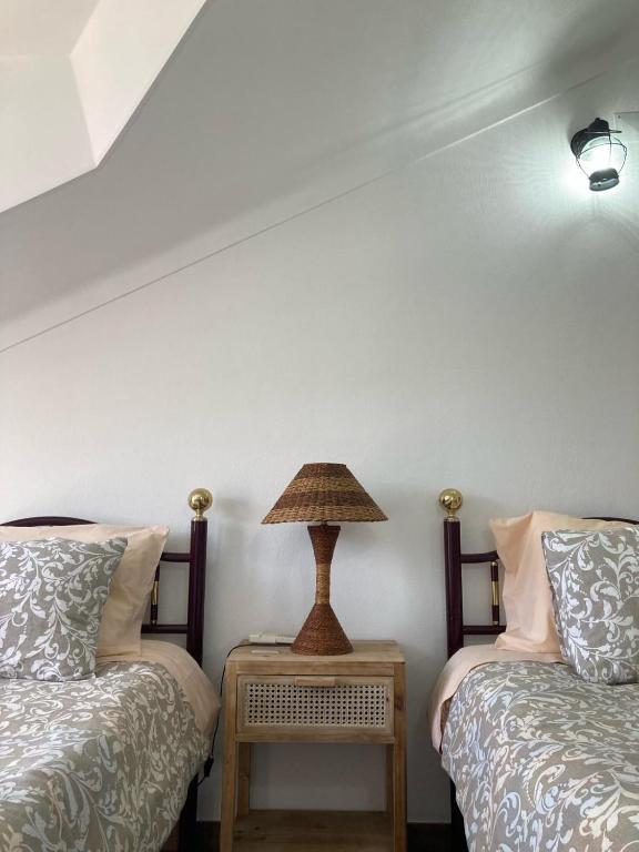 a bedroom with two beds and a lamp on a table at Casa da Nazaré in Portinho da Arrábida