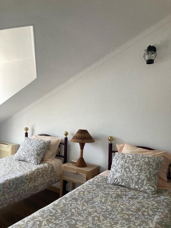 a bedroom with two beds and a lamp on a table at Casa da Nazaré in Portinho da Arrábida