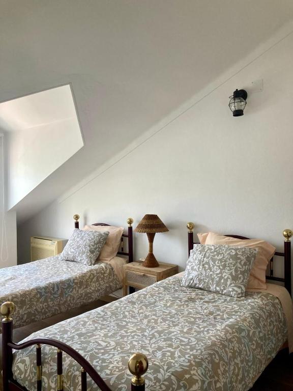 a bedroom with two beds and a lamp at Casa da Nazaré in Portinho da Arrábida