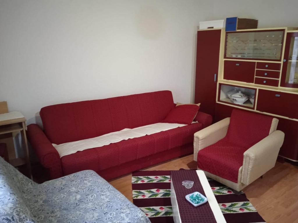 ein Wohnzimmer mit einem roten Sofa und einem Stuhl in der Unterkunft Dedina Luka in Valjevo