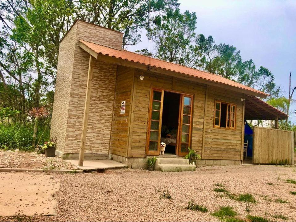 a small house with a dog standing in the doorway at Bombinhas, Casa mobiliada 1 quarto in Bombinhas