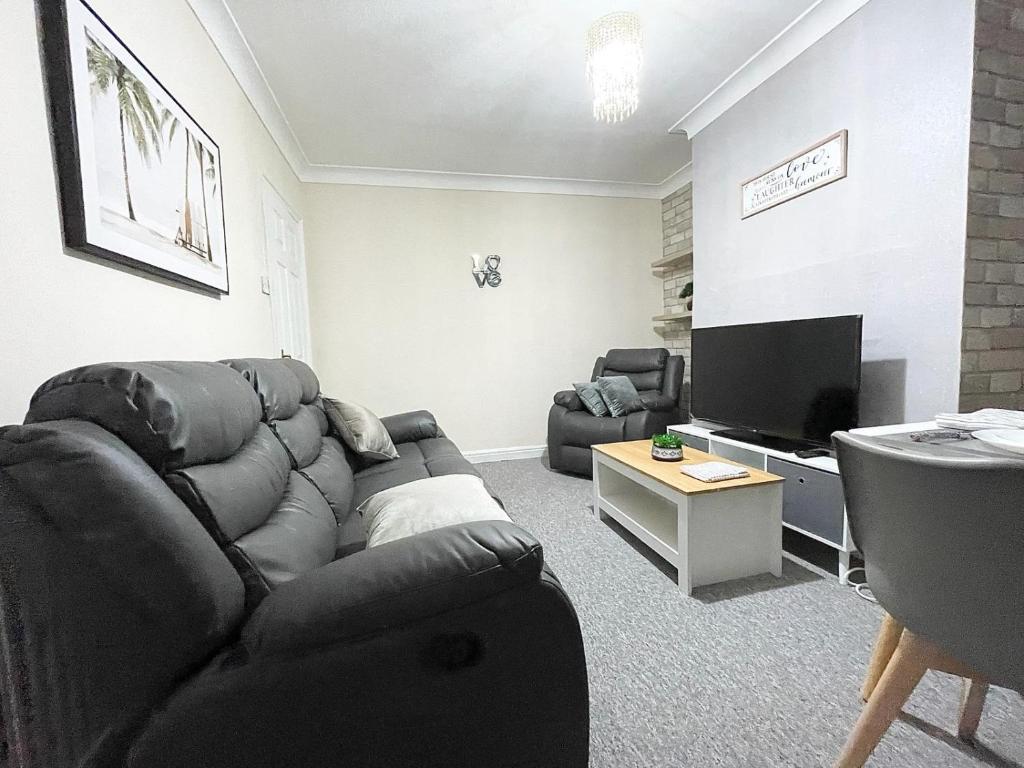 a living room with a couch and a flat screen tv at Cosy home, family & contractor friendly 4 bedroom near Leeds centre, sleeps 7 in Leeds