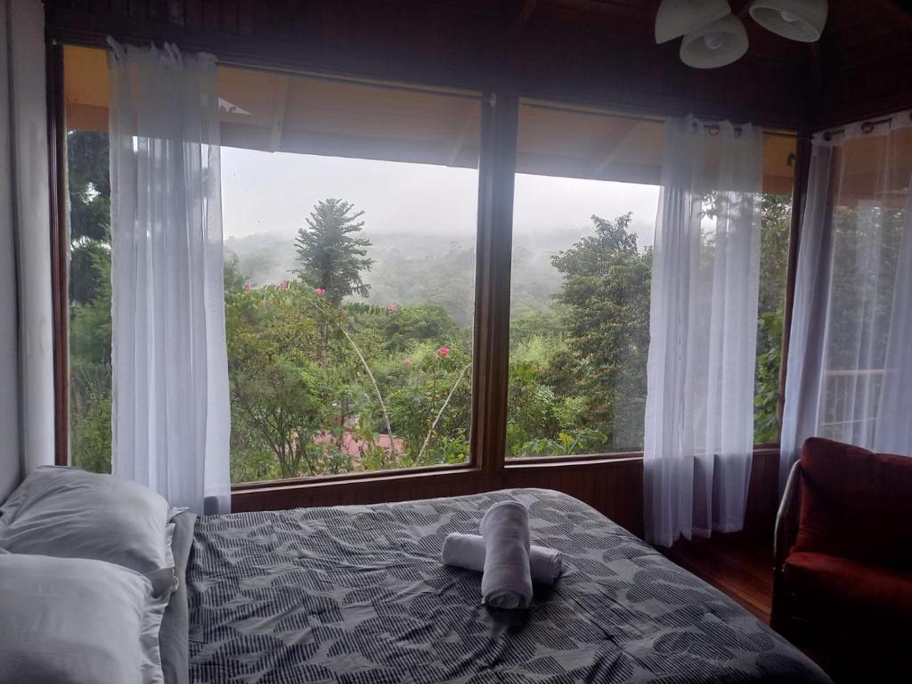 1 dormitorio con cama y ventana grande en Finca Valle Arcoiris, en Heredia