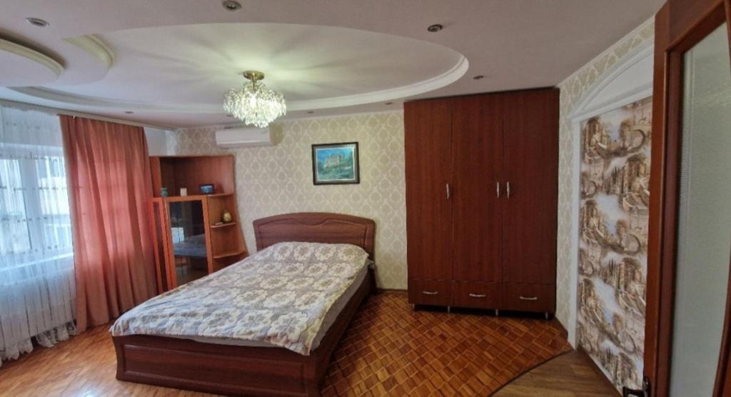 - une chambre avec un lit et un lustre dans l'établissement Уютные апартаменты, à Chişinău