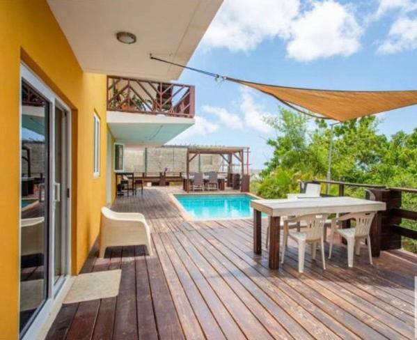 a wooden deck with a table and chairs and a pool at Two Bedroom app Villa Islandessa in Willemstad