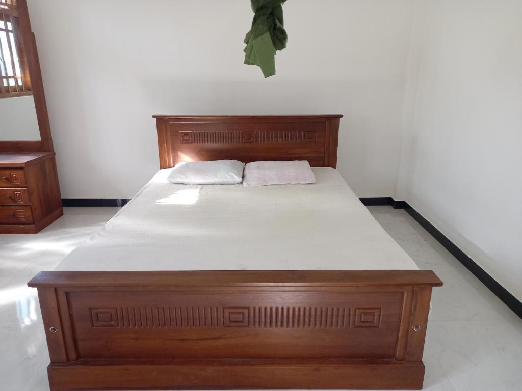 uma cama de madeira com duas almofadas brancas em Chamara home stay em Ratgama Hegoda