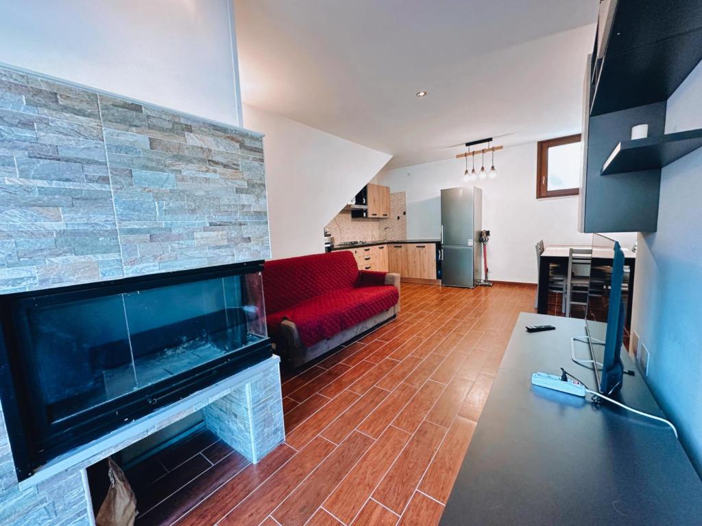 Finestra su Villalago في Villalago: غرفة معيشة مع موقد وأريكة حمراء