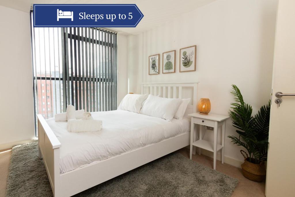 a white bedroom with a white bed and a window at Central Gem: Cosy 2BR with Private Balcony in Manchester