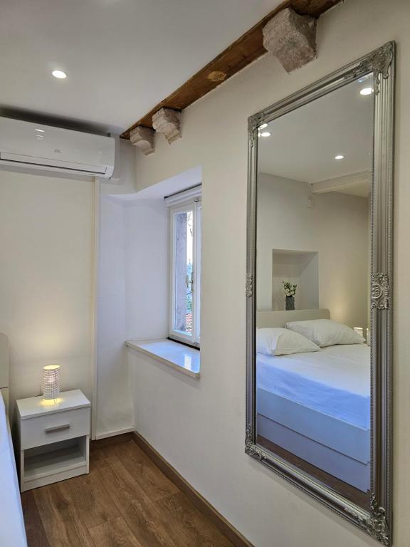 um espelho num quarto com uma cama e uma janela em Apartment Zakrjan in Old town Korčula em Korčula