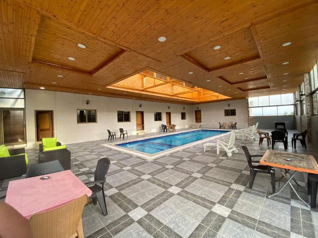 a pool in a room with tables and chairs at مزارع وشاليهات للايجار في جرش in Jerash