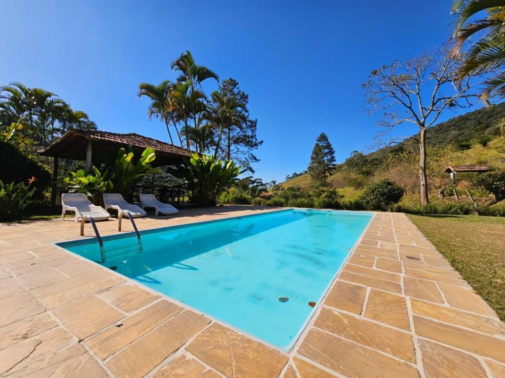 a swimming pool with two chairs and a house at Hotel Fazenda Upã Moña in Vassouras