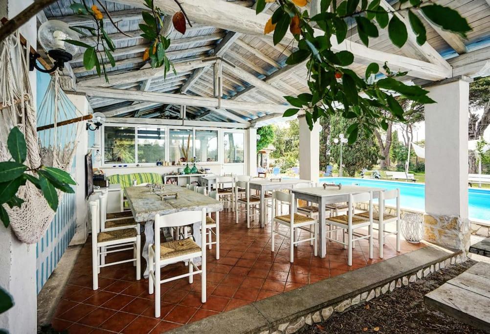 un patio con mesas y sillas y una piscina en Villa Collina dei Pini, en Lido dei Pini