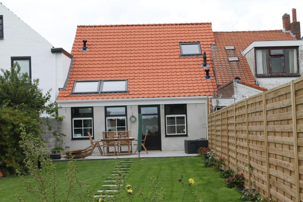 a house with an orange roof and a yard at Huisje Zeertevree in Nieuwvliet