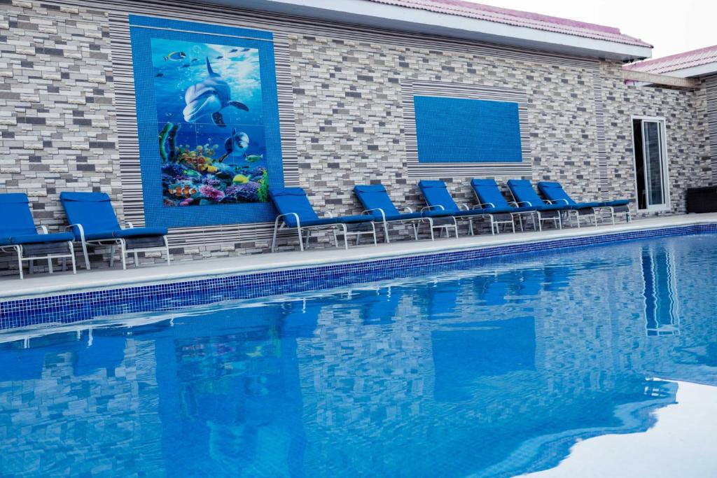 een zwembad met blauwe ligstoelen naast een gebouw bij Andalusia farm in Al Rahba