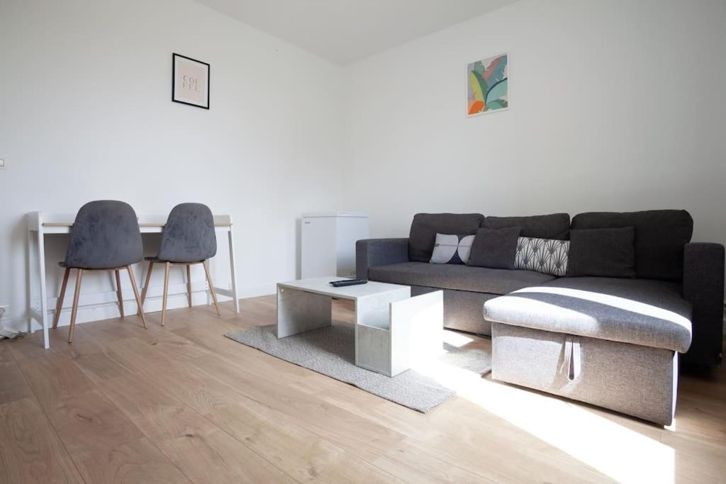 ein Wohnzimmer mit einem Sofa, einem Tisch und Stühlen in der Unterkunft 2 pièces Cosy - proche RER A - proche Paris in Houilles