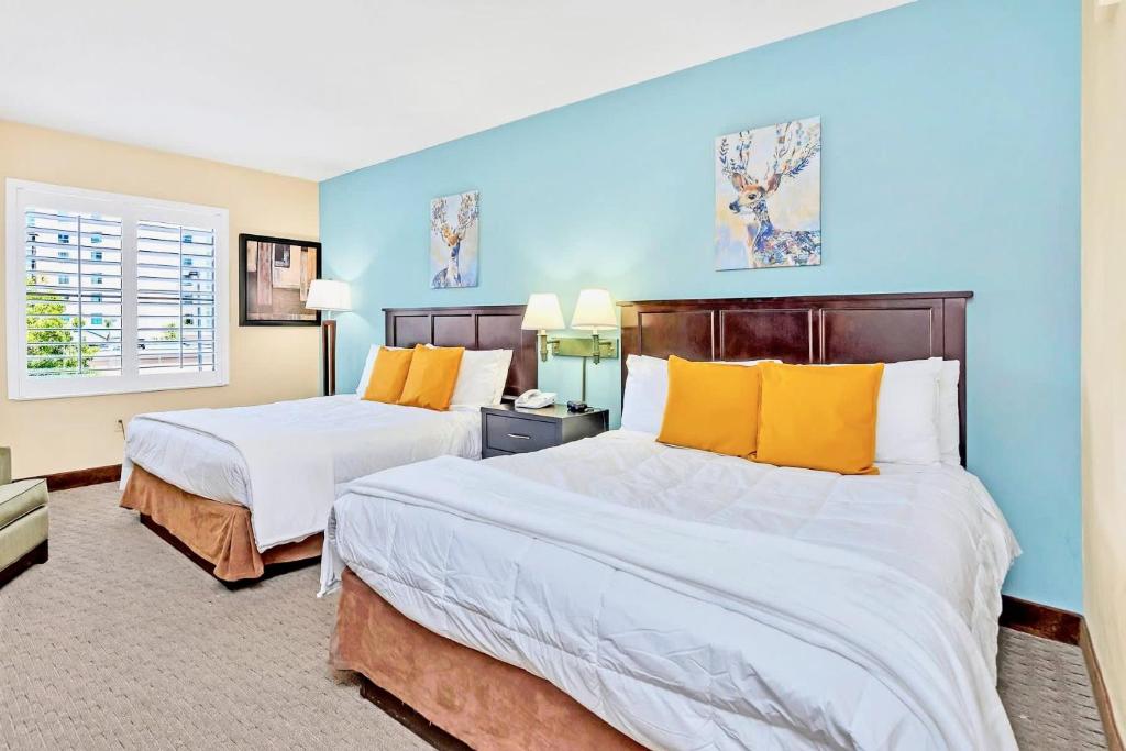 two beds in a room with blue walls and yellow pillows at Apt Close to Universal Studios with Hot tub Pool in Orlando