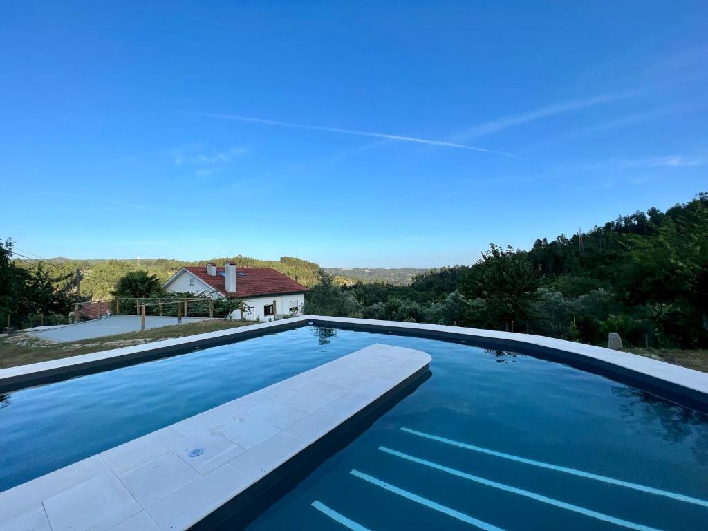 a swimming pool with a house in the background at Ecorustics stay - Casa Estêvão in São Pedro do Sul