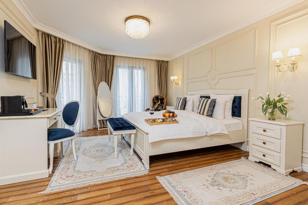 a bedroom with a white bed and a desk and chairs at Grant Boutique Hotel in Arad