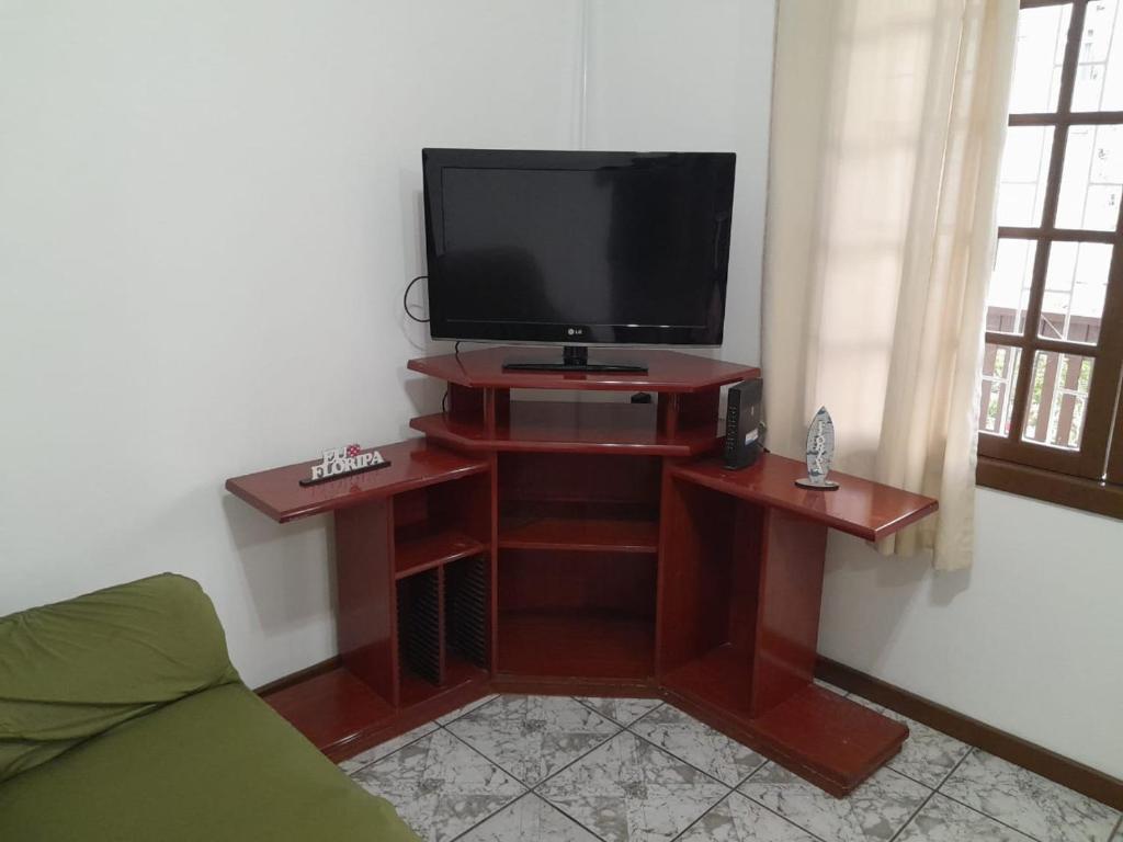 een woonkamer met een tv op een houten standaard bij Casa Trindade UFSC in Florianópolis