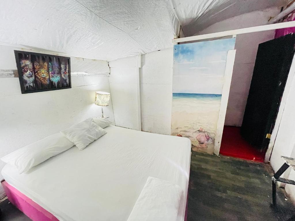 Un dormitorio con una cama blanca y una pintura en la pared en Hostal la Canoa en Playa Blanca